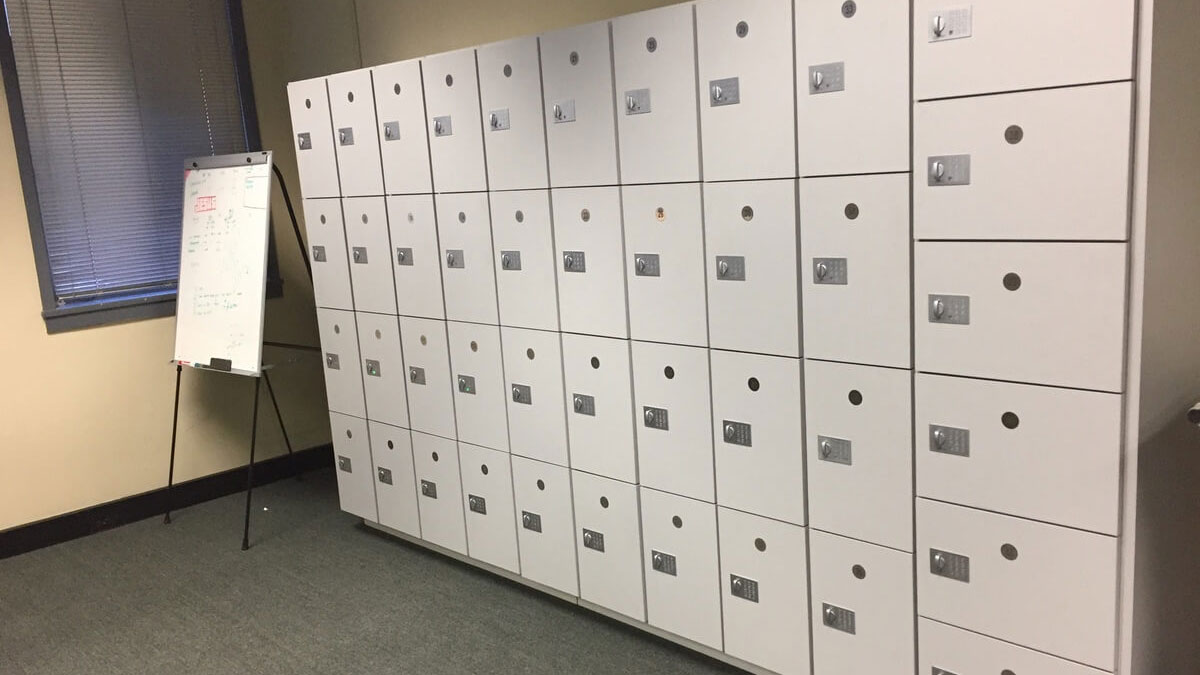 White digital combination lockers in a private office corner with flip chart and carpeted floor