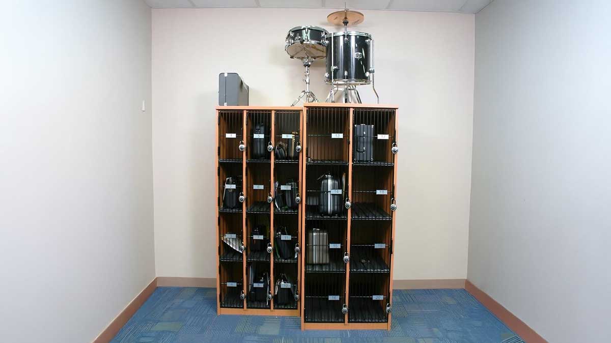 Compact band instrument lockers with black wire doors and percussion instruments stored on top