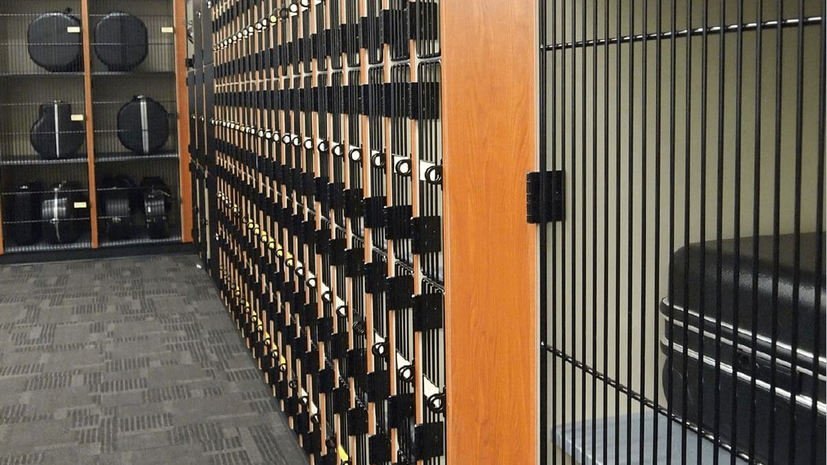 Close-up view of wooden musical instrument storage lockers with vertical wire doors in a school band room