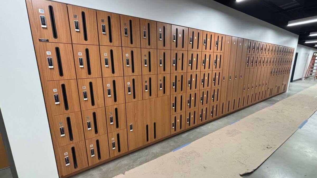 Wall of woodgrain band storage lockers equipped with digital keypad locks in a music facility hallway