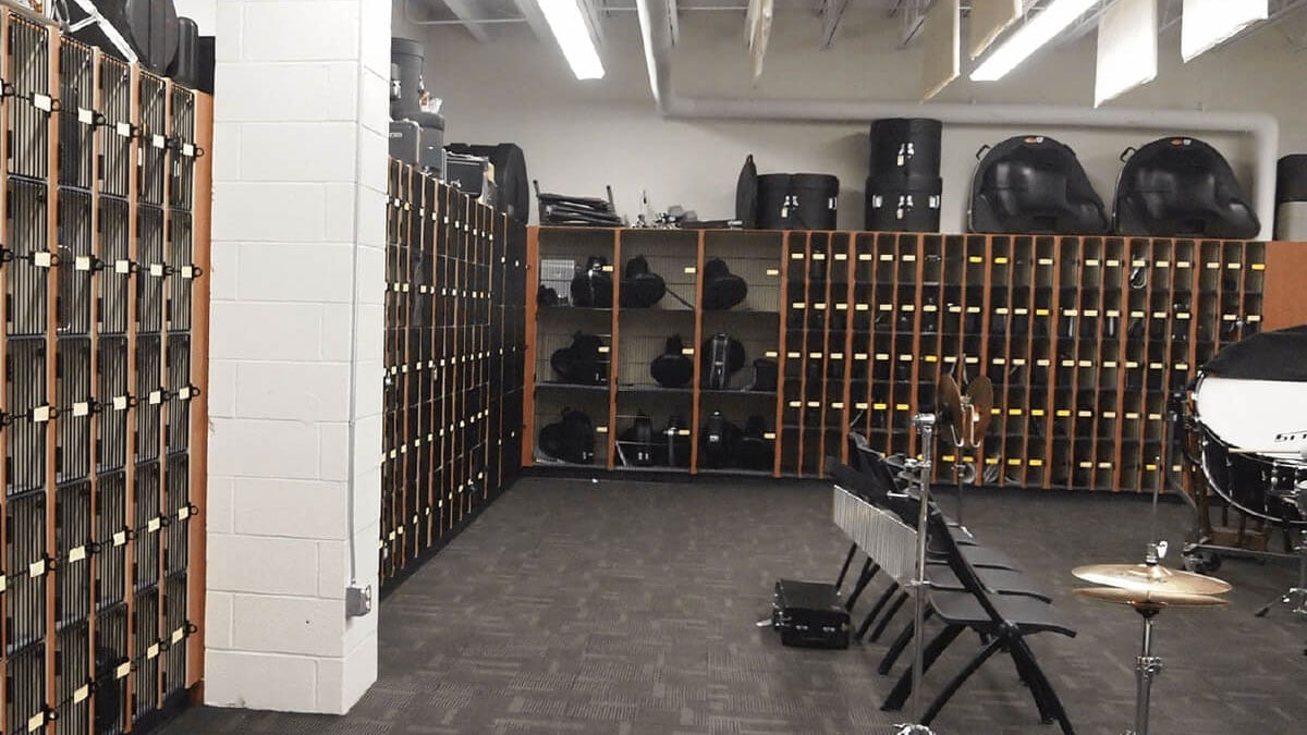Spacious band storage room with dozens of musical instrument lockers and percussion storage against the walls