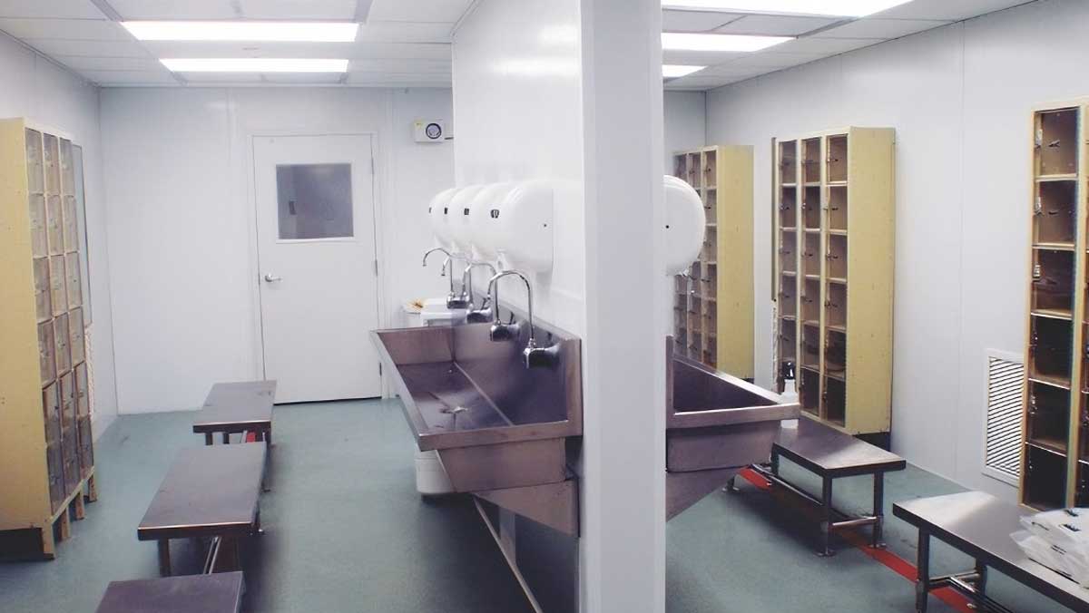modular changing room featuring stainless steel wash station with multiple sinks and locker benches for employee hygiene
