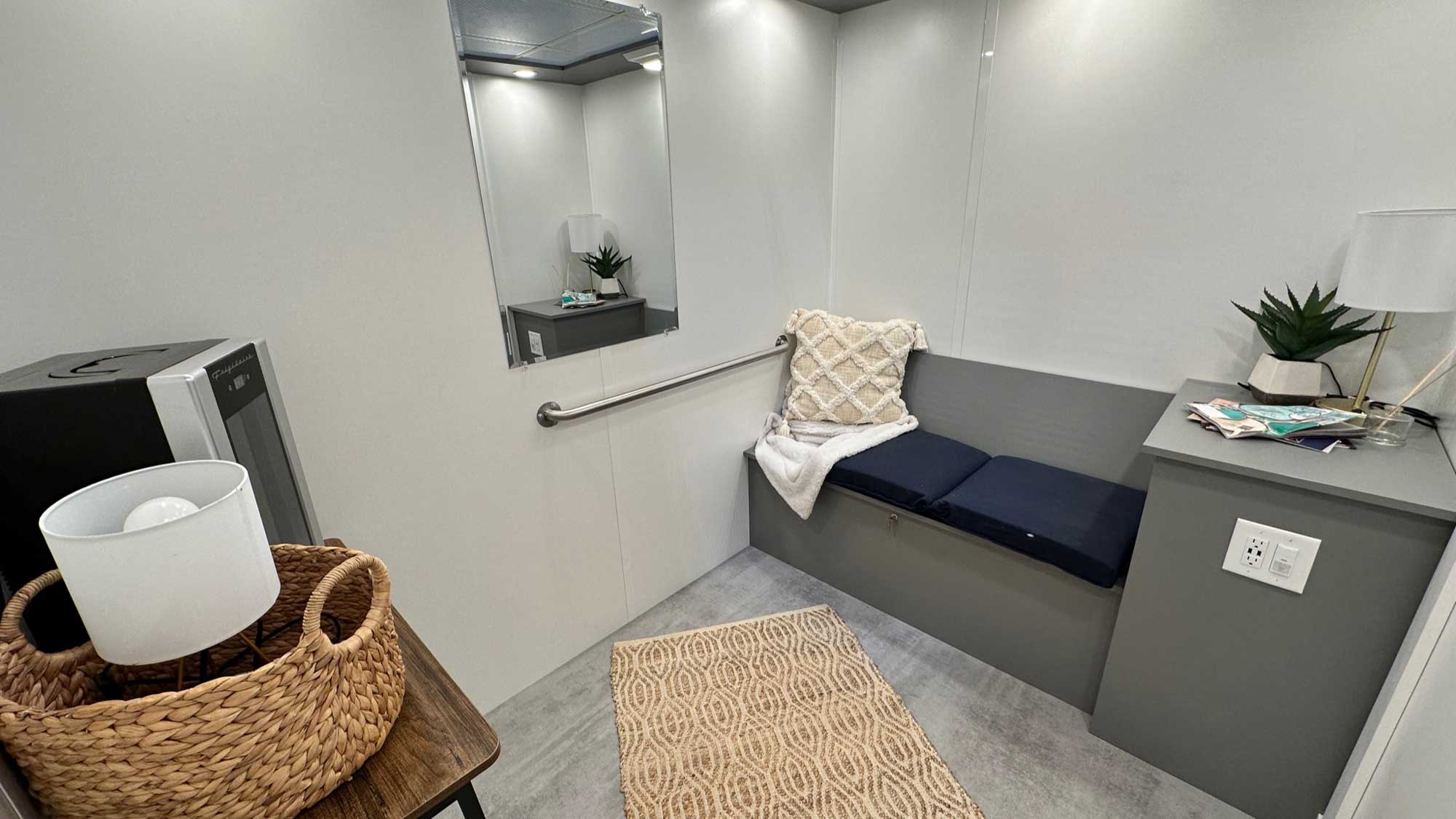interior of lactation pod with bench seating, mirror, and power outlet for nursing equipment setup
