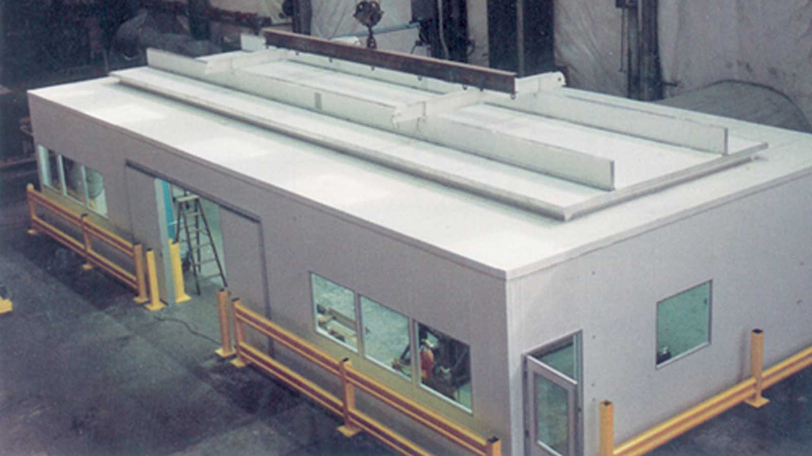 modular cleanroom enclosure with pass-through door and safety barriers inside industrial workspace