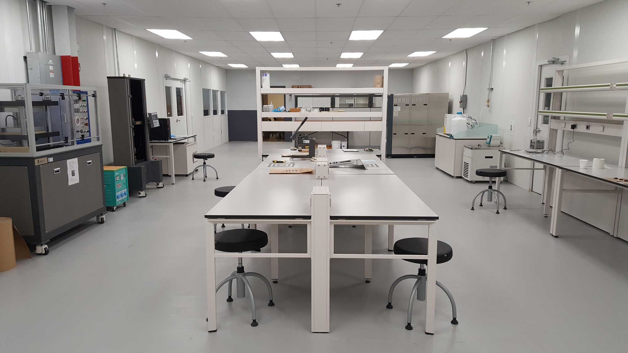 cleanroom research lab interior with central worktables, stools, and bench-mounted equipment
