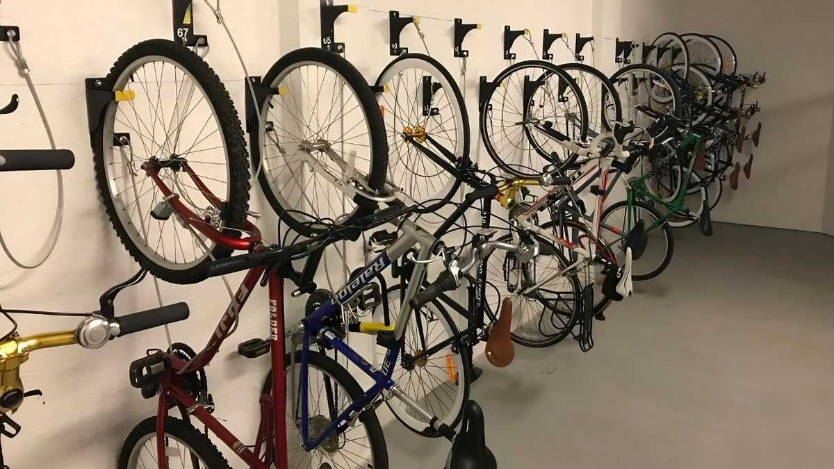 numbered wall mounted bike hook and cable storage system securing bicycles by front wheel for efficient space use