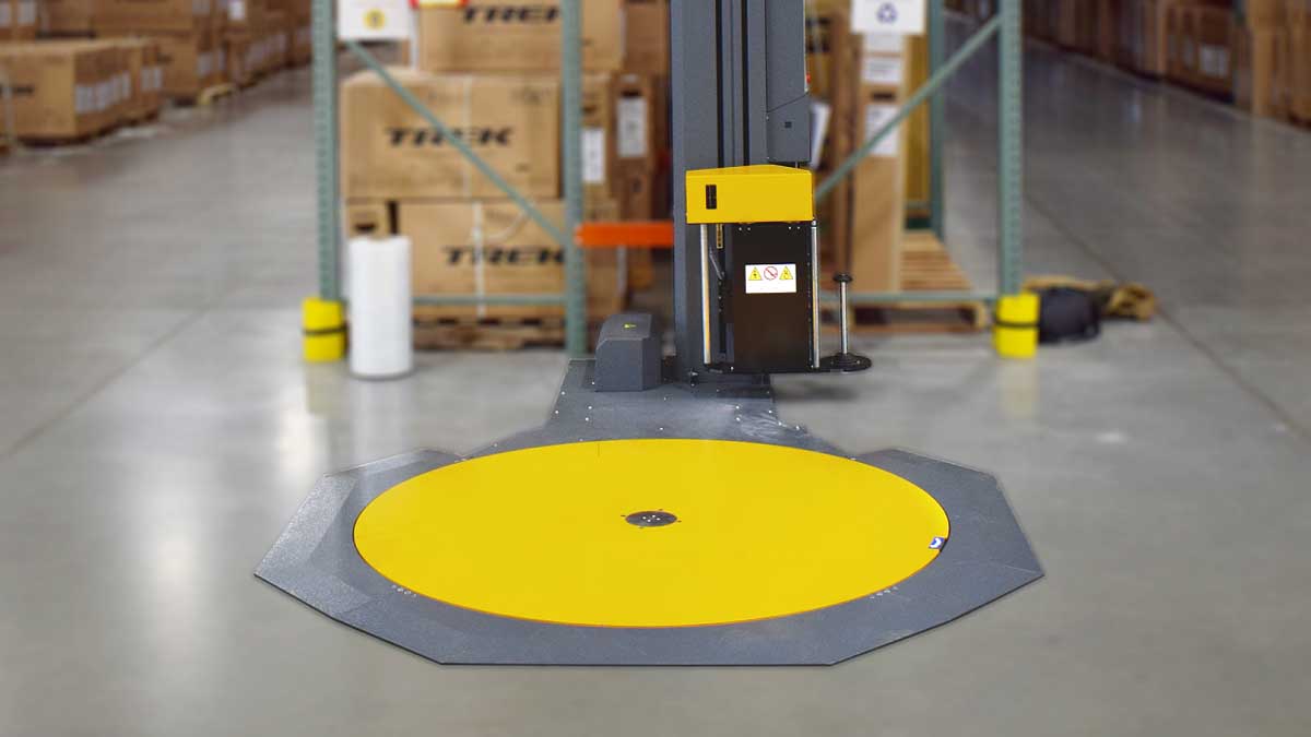semi-automatic pallet wrap machine installed in warehouse for secure pallet load containment