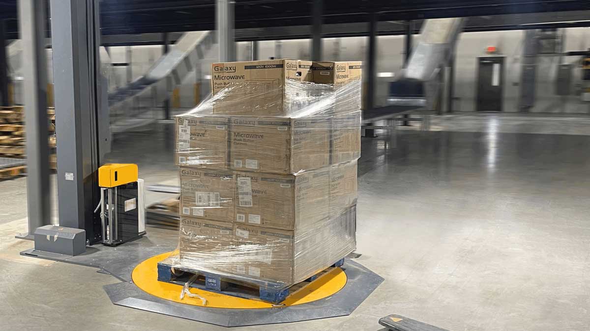 electric pallet jack positioning pallet onto wrap machine turntable for wrapping preparation