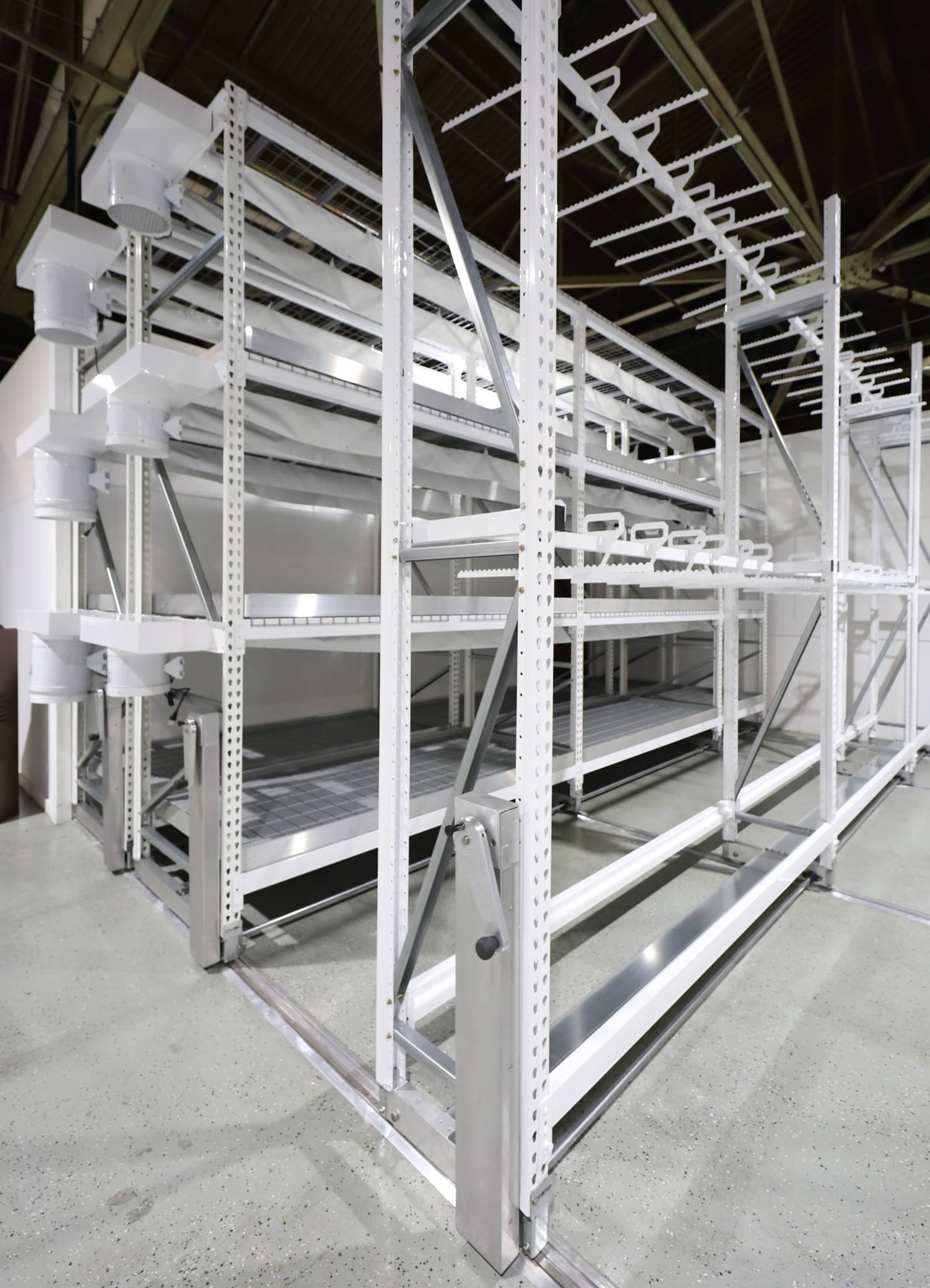 Mobile and fixed vertical grow racks in a cannabis cultivation room with stacked canopy tiers, LED lighting, and service aisles.