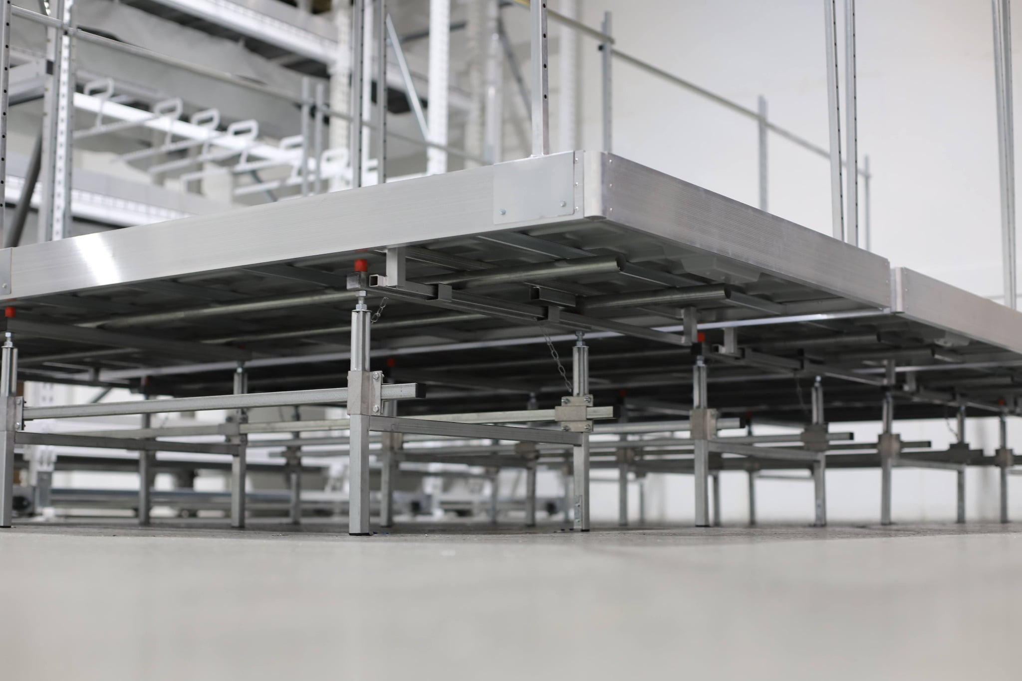Elevated storage platform support frame with adjustable legs for industrial floor installation