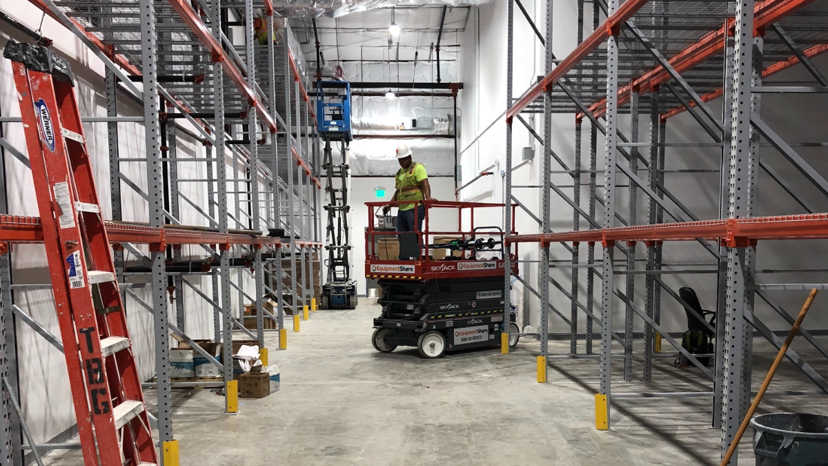 Worker on scissor lift installing high density storage solutions