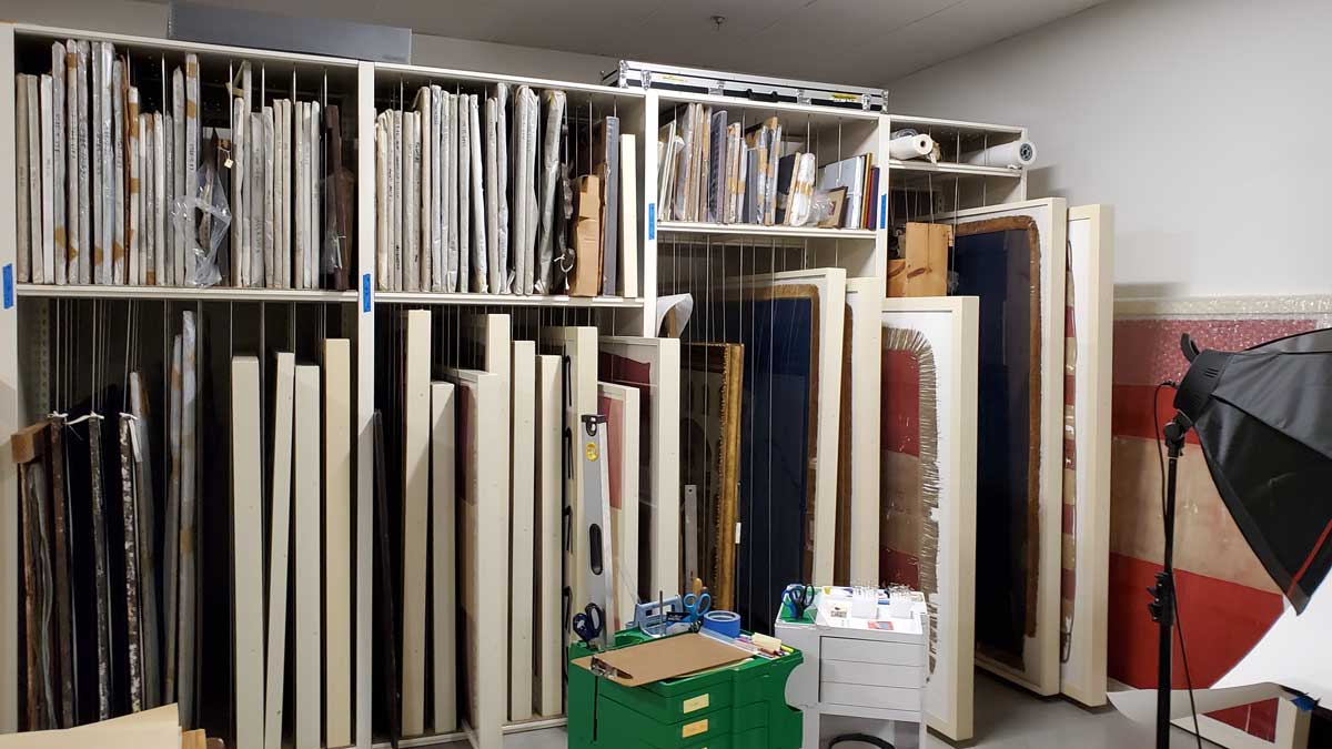 Shelving with rod dividers separating unframed works