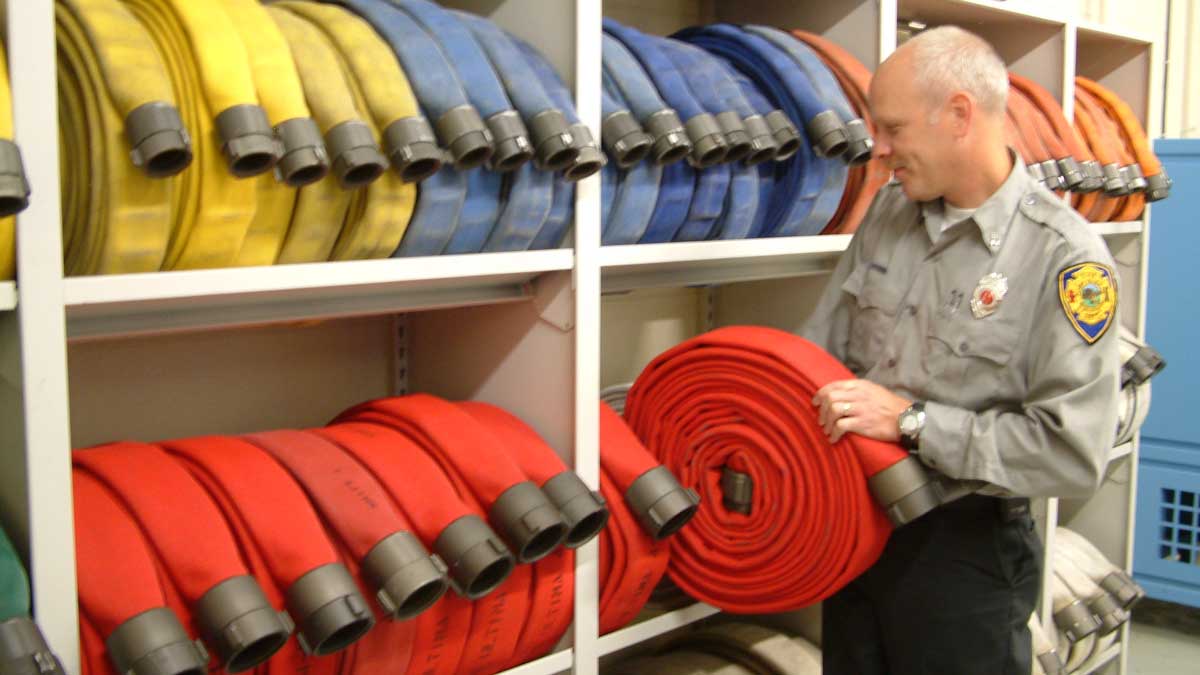 Fort Atkinson Fire Department’s hose storage solution: neatly coiled red, yellow, blue, and white hoses on a modular shelving system.