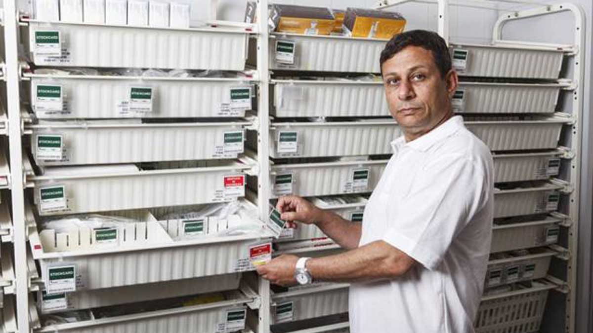 technician selecting labeled medical supply bin from storage rack to organize inventory