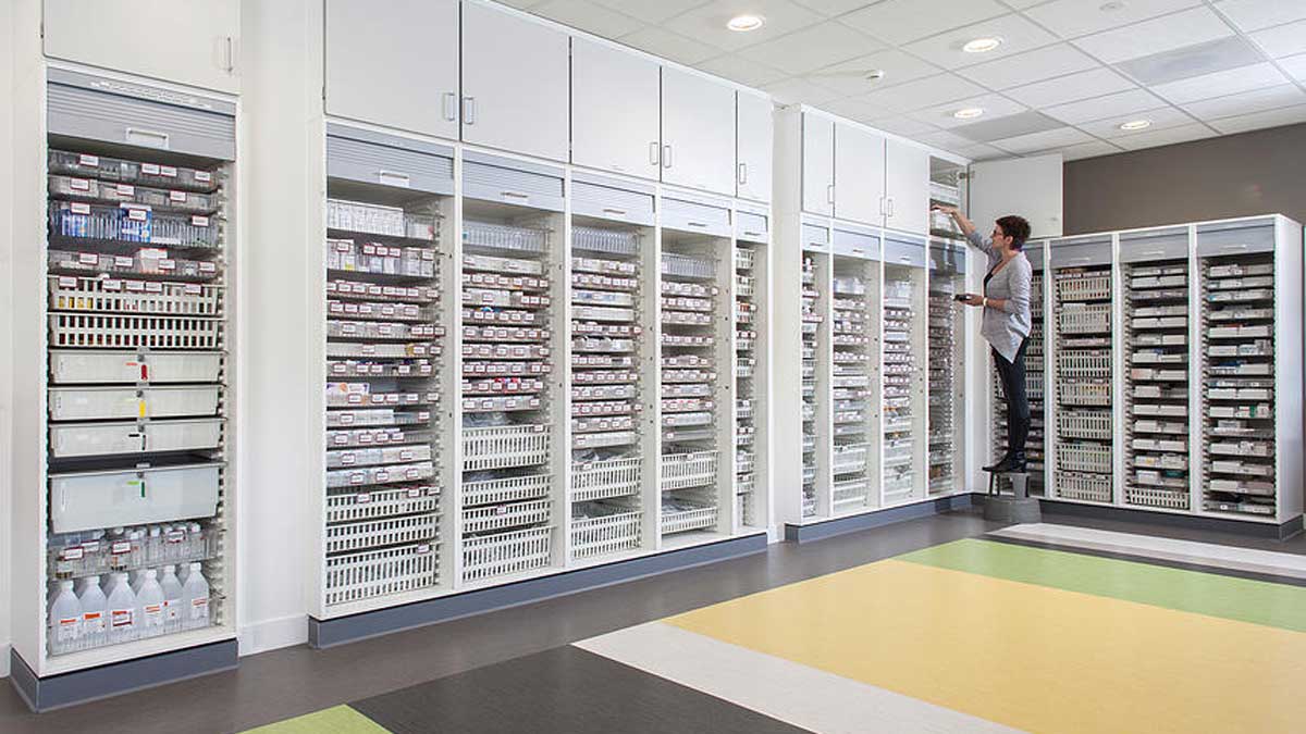 pharmacist accessing overhead cabinet with supply compartments to maximize pharmacy storage space