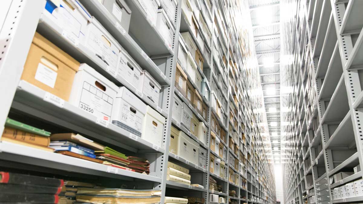 tall library shelving filled with archival boxes in high-density storage configuration