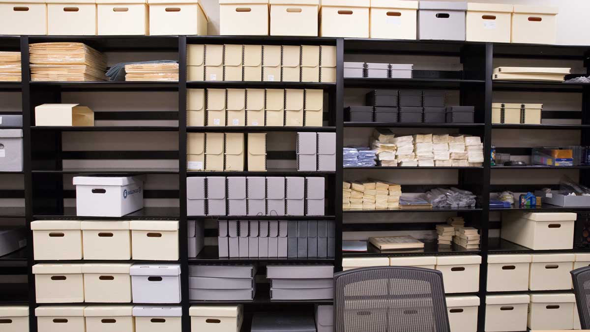 Academic file storage shelves holding labeled document boxes