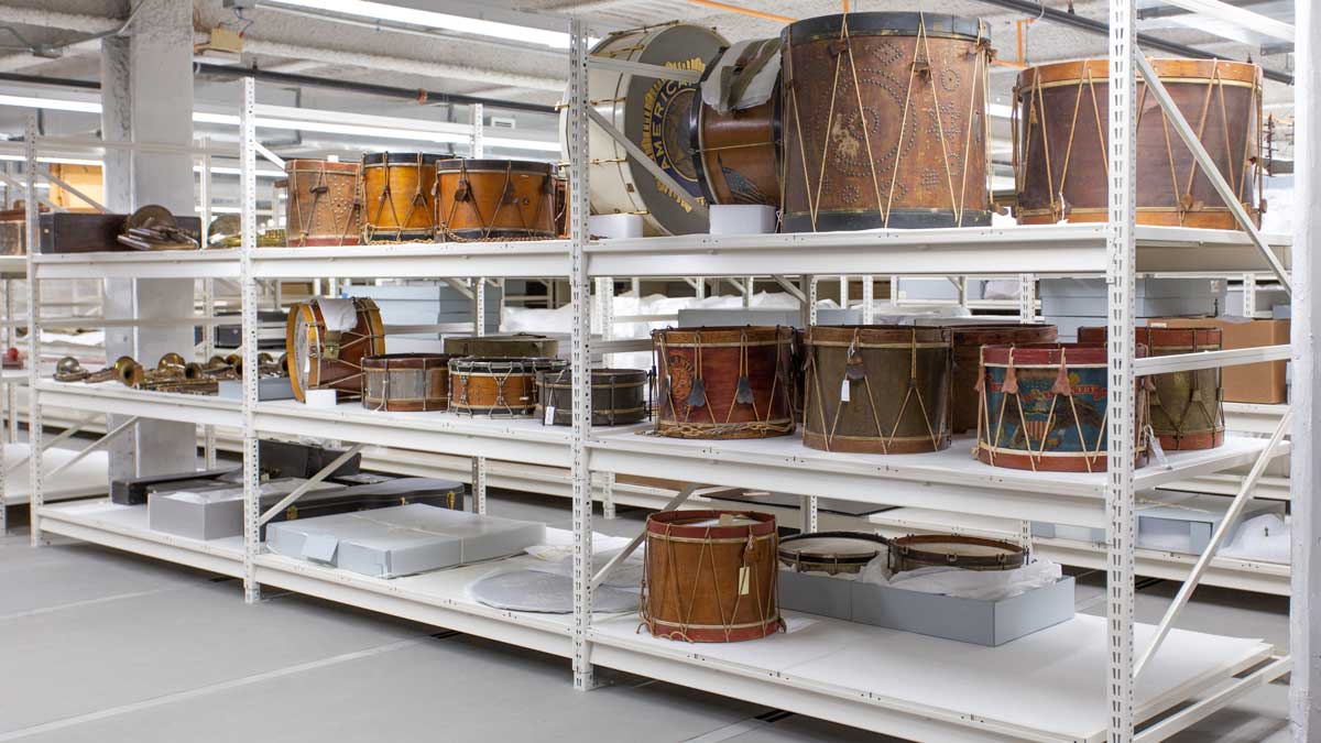 white archival storage shelving holding museum drum collection with protective support surfaces