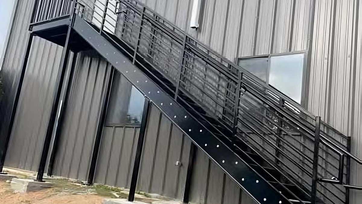 exterior emergency exit steel staircase with safety rails mounted against a brick industrial wall
