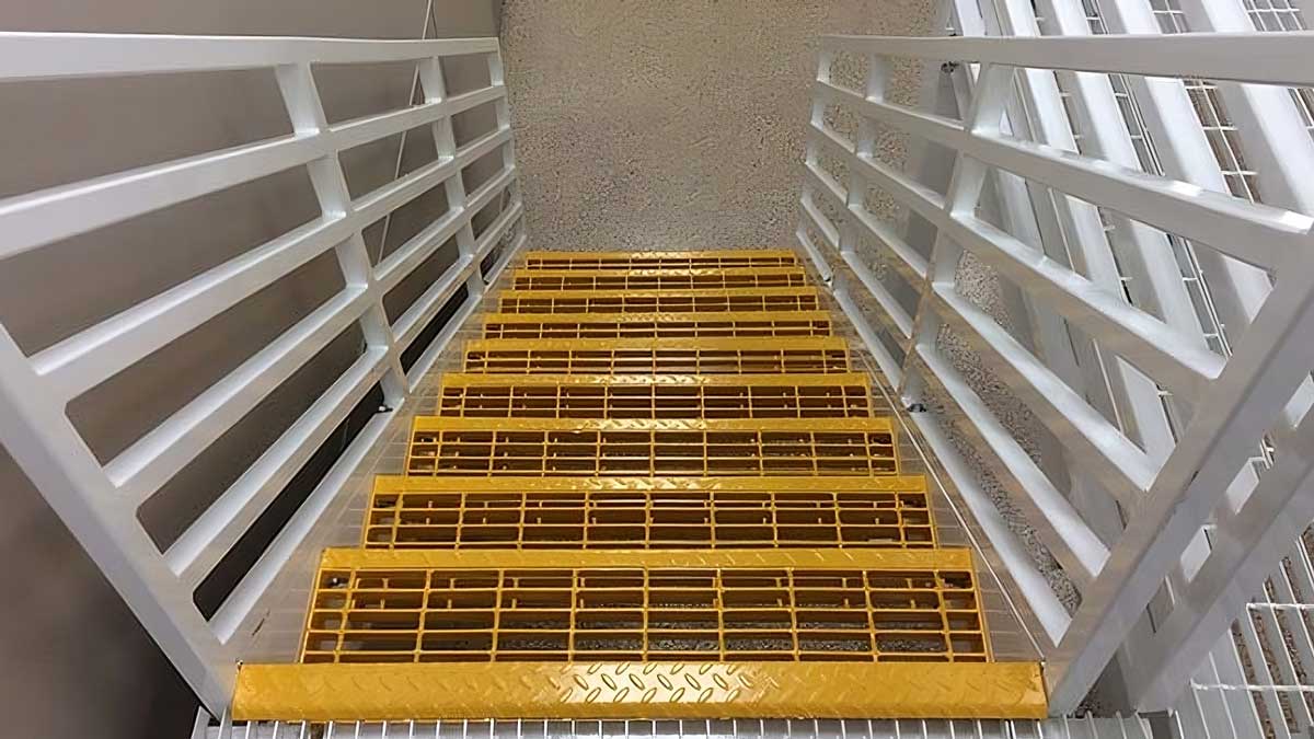 U-shaped industrial mezzanine staircase with grated steps and yellow safety guardrails in a warehouse