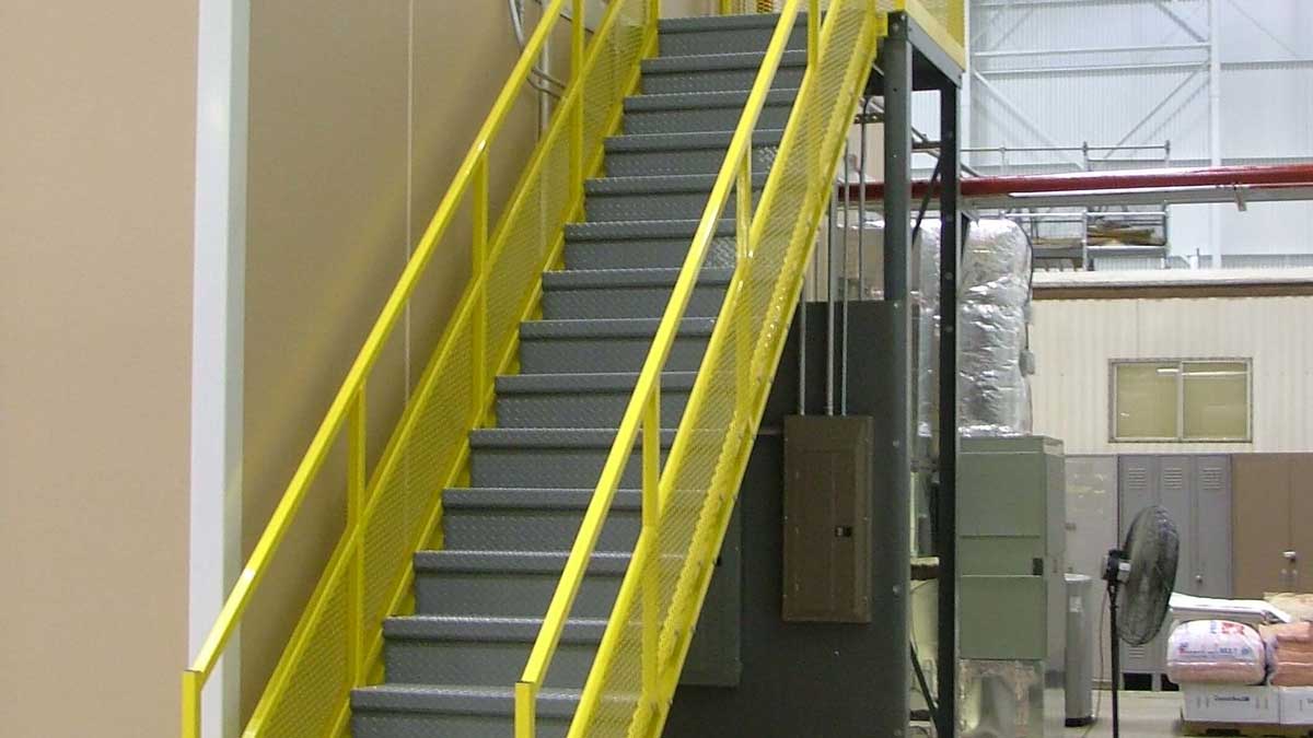 Gray steel industrial stairs leading to a mezzanine work platform