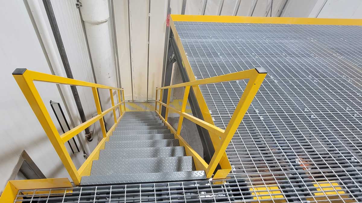 industrial mezzanine with grated platform and stair access designed for safe upper level entry in warehouse facilities