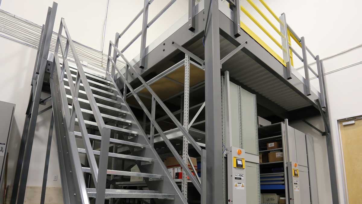 steel mezzanine with stair entry and integrated shelving to increase warehouse storage and accessibility