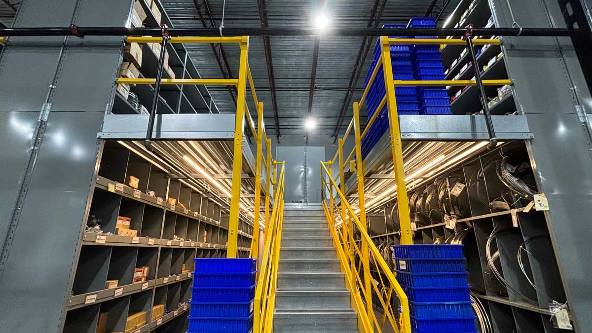 dual-level shelving system with central stair access and integrated mezzanine for organized parts storage