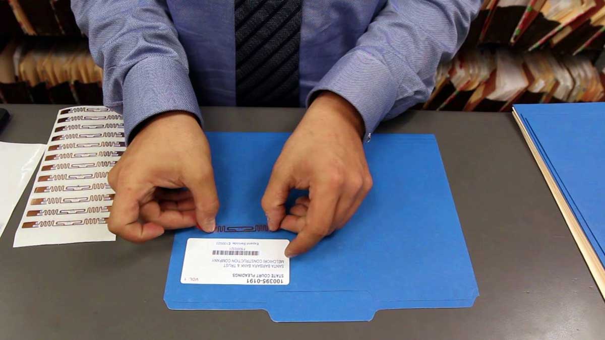 office worker placing RFID tag on labeled folder to enable digital tracking and retrieval