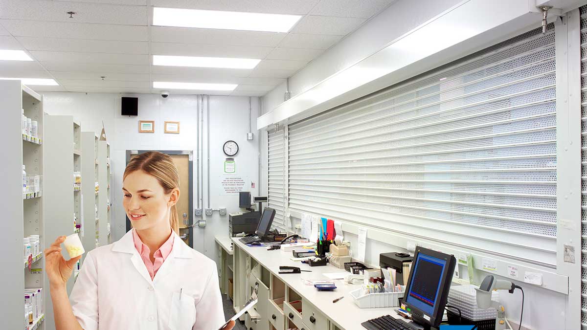 pharmacy technician working behind closed rolling shutter for secure medicine storage access control