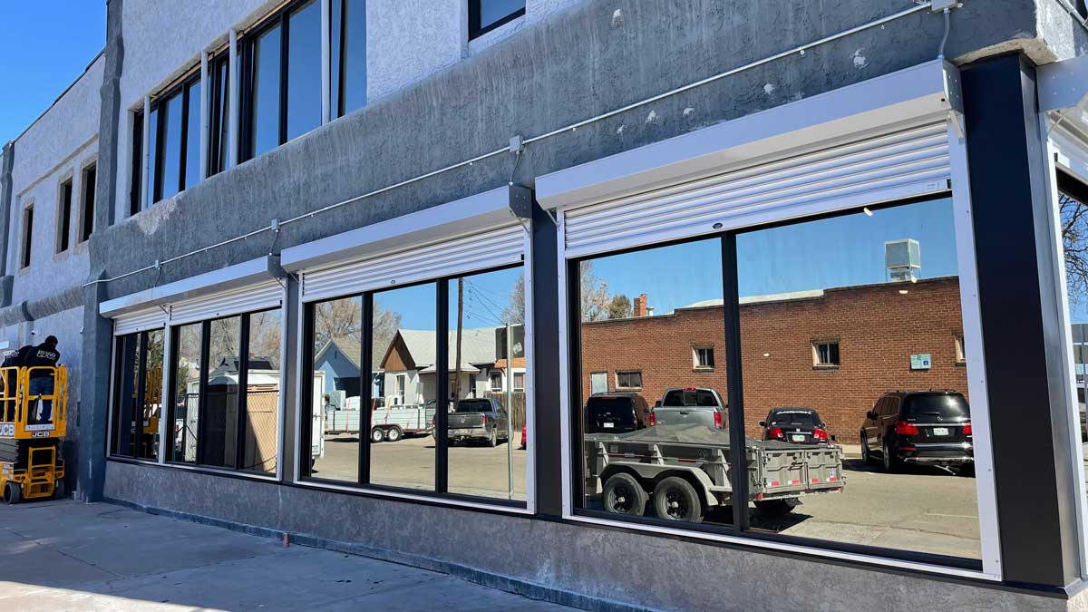 rolling security doors being installed on commercial glass windows for exterior break-in resistance