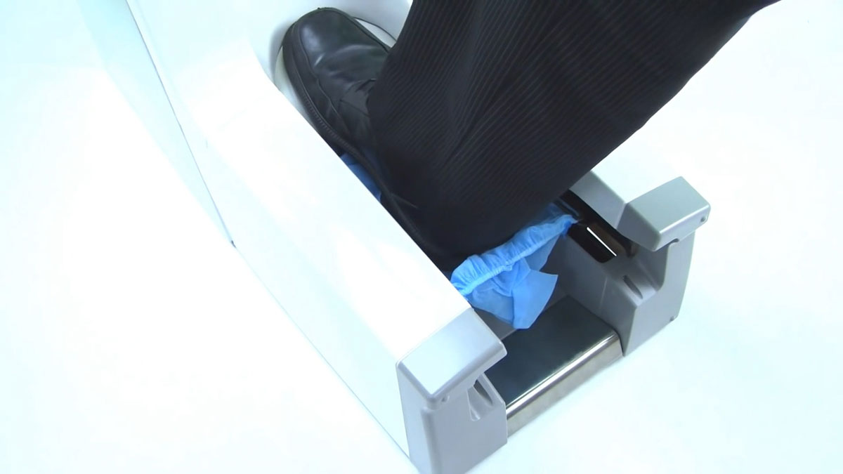 User stepping into a shoe cover dispenser at a cleanroom entry