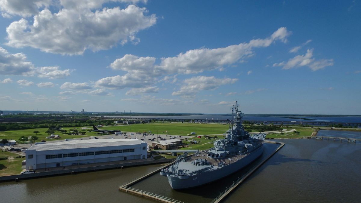 Battleship museum waterfront Alabama with naval vessel docked beside channel