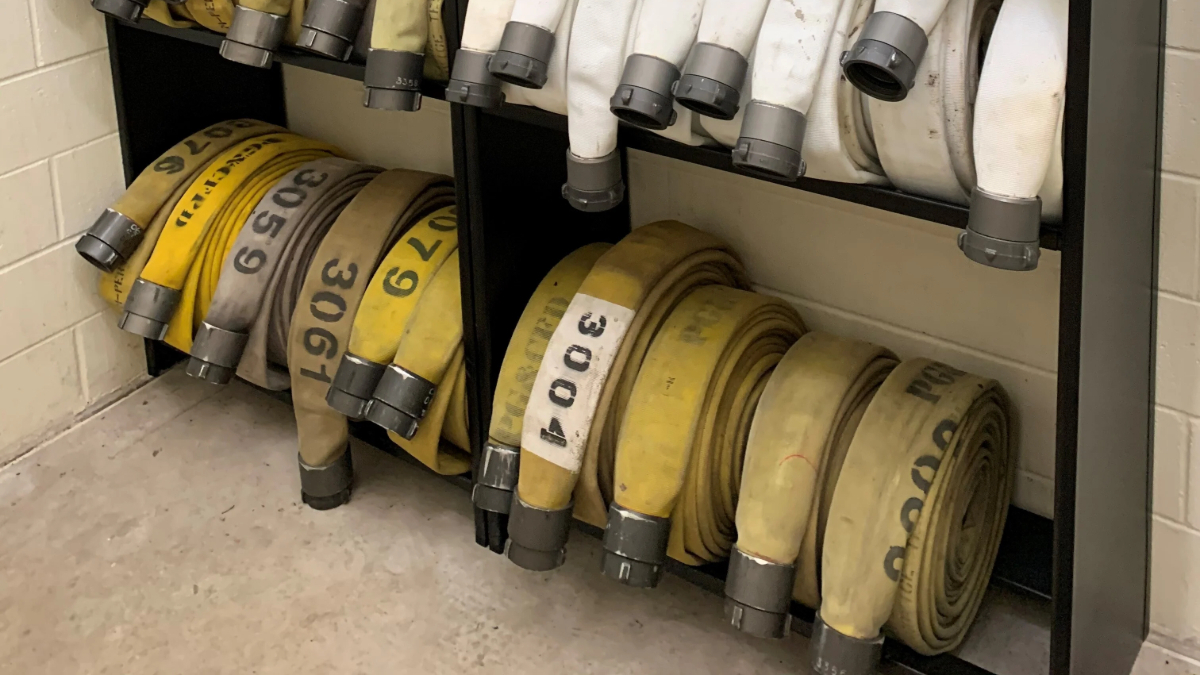 Fire hose storage rack for organized hose rolls and emergency equipment access